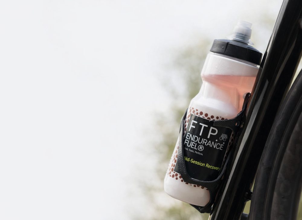 FTP Power Fluids carbohydrate and electrolyte drink mix pack next to a filled sports bottle