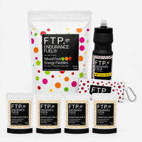 Race Week Kit contents with 1kg Mixed Fruit energy pastille pouch, four Power Fluids Core Neutral Citrus caffeinated pouches, matte black bottle and Adventure Pouch