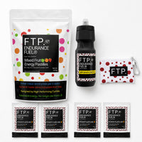 Race Week Kit contents with 1kg Mixed Fruit energy pastille pouch, four Power Fluids Mix Tart Cherry sachets, matte black bottle and Adventure Pouch