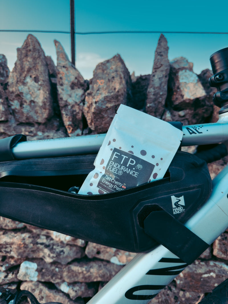 FTP Tart Cherry Energy Pastilles in a bike frame bag against a stone wall