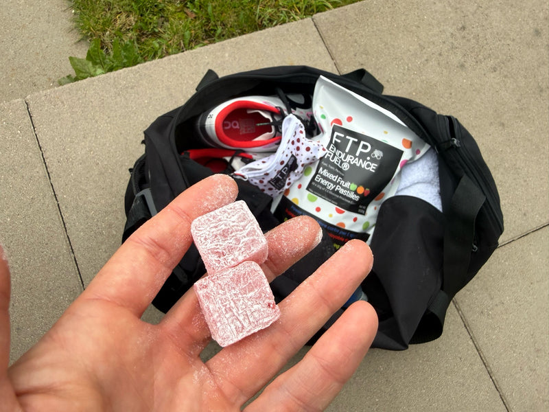 Tart Cherry Energy Pastilles in hand over a packed race kit bag